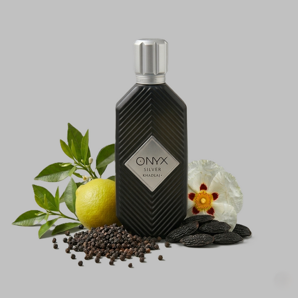 Khadlaj Onyx Silver perfume in a black bottle with a silver cap, surrounded by fresh lemon, green leaves, and flowers on a gray background.
