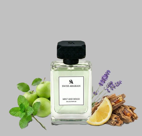 Swiss Arabian Mint and Wood perfume bottle with green apples, lemon, lavender, and wood pieces on a gray background