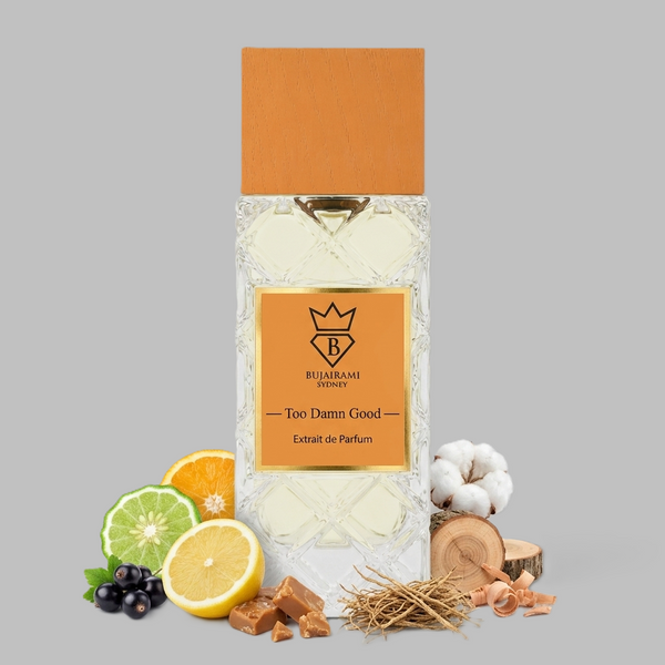 A bottle of Ruikarach & Honey 'Too Damn Good by Bujairami' Extrait de Parfum centered on a gray background, surrounded by its scent ingredients including citrus slices, cotton bolls, wood pieces, dried herbs, and dark berries.